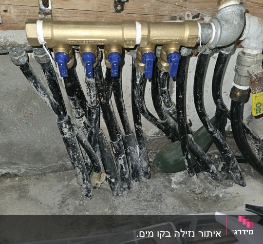 ברזים כחולים על צינורות שחורים במערכת אינסטלציה